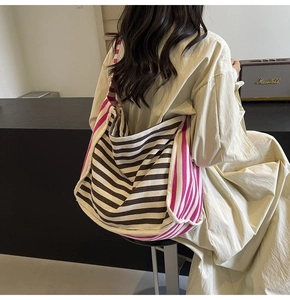 Detailed back view of a large pink and brown striped canvas tote bag styled with a dress
