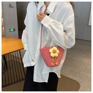 Detail of red and white woven bucket bag with large yellow 3D floral decoration