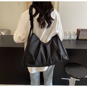 Dettaglio di una borsa hobo nera con spalline arricciate e finitura in nylon setoso