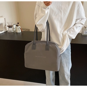 Deep grey canvas tote bag with Enjoy Life print carried by a model in casual style