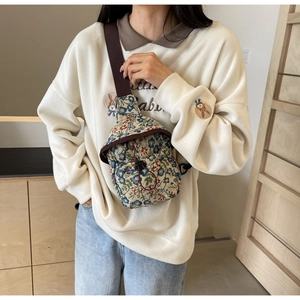Detail of floral tapestry crossbody bag showing drawstring closure and fabric texture
