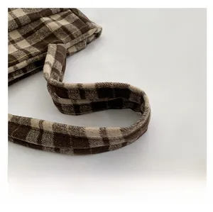 Détail de la poignée cousue épaisse et du tissu en laine tissé du sac à main à carreaux