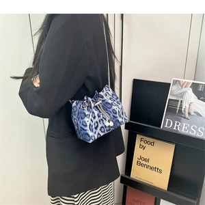 Detail of blue leopard print bucket bag with silver chain strap and pearl drawstring charm