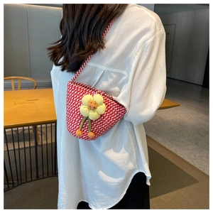 Detail of red and white woven bucket bag with a cute yellow flower charm pendant