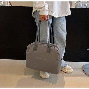 Close-up of grey fabric travel bag with Enjoy life and travel embroidery and handles