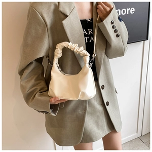 Detail view of cream PU leather handbag with ruffled handle and detachable shoulder strap