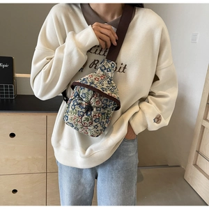 Detailed close-up of a floral crossbody bag featuring a drawstring closure and brown strap