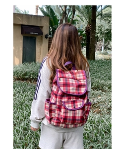 Close-up of red and white checkered backpack with purple trim in an outdoor setting