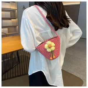 Detail of red and white houndstooth knit bucket bag with a 3D yellow floral accent