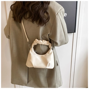 Detail of a beige PU leather crossbody bag featuring a unique pleated top handle design