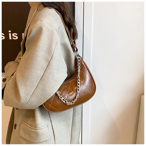 Détail du sac croissant matelassé marron foncé avec une chaîne décorative argentée