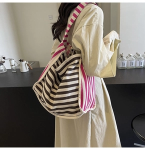 Detailed close-up of a striped canvas tote bag with wide shoulder strap in cafe setting