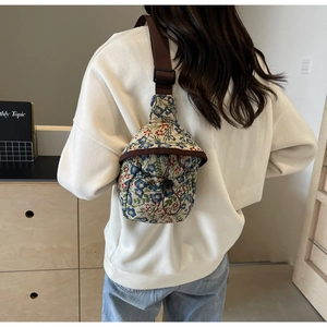 Detailed close-up of floral jacquard fabric texture and drawstring on a crossbody bag