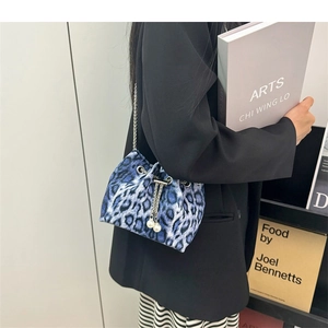 Detail view of blue leopard bucket bag with silver chain and white pearl charms