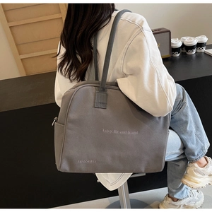 Close-up of grey canvas tote bag featuring Enjoy life and travel embroidered text