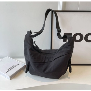 Detail view of black crescent crossbody bag with braided rope zipper and nylon texture