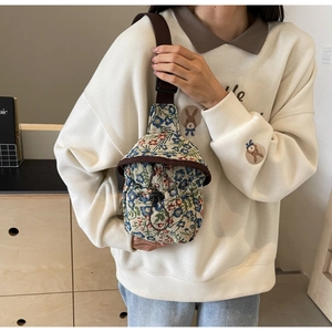 Detail of floral tapestry crossbody bag with drawstring pocket and brown strap