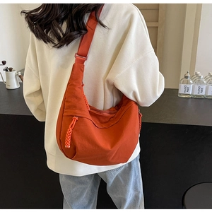 Detail view of the burnt orange nylon dumpling bag showing adjustable strap and large capacity