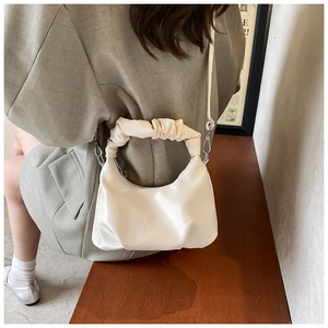 Detailed view of cream white PU leather handbag featuring a ruched scrunchie handle design