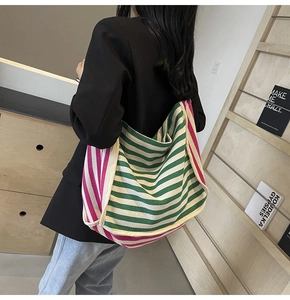 Detail of a large canvas tote bag with green and white stripes and a thick shoulder strap