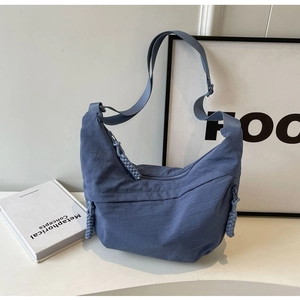 Detail of navy blue nylon dumpling bag with adjustable strap and woven zipper pull