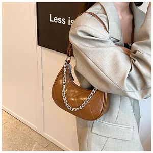 Détail du sac hobo en cuir PU marron matelassé avec chaîne argentée porté par un modèle