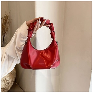 Close-up of a red pleated handbag with a glossy metallic finish and a unique cloud handle