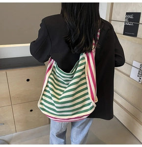 Green and pink striped canvas shoulder bag shown on model for a casual styling view