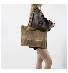 Détail macro du sac cabas en laine avec motif à carreaux marron et grande poche avant