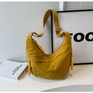 Detail of a ginger yellow crescent canvas bag with hand-woven rope zipper pulls