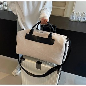 Detail of canvas travel tote with leather handles on a white suitcase, stylish design