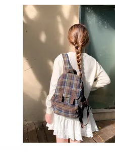 Detailed back view of a vintage plaid backpack with leather straps on a model