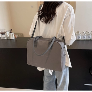 Detail of grey canvas tote bag with adjustable shoulder strap and travel text