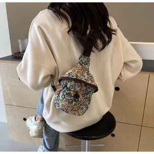 Detailed macro view of the floral fabric texture and drawstring closure on the crossbody bag