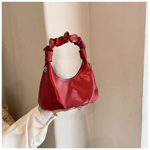 Detail of a red hobo bag with glossy finish and unique scrunchie cloud handle design