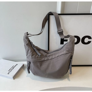 Detail of grey nylon crescent bag showing woven zip pulls and adjustable strap