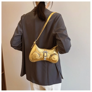 Close-up of golden Y2K underarm bag featuring silver rivets and large carved metal buckle