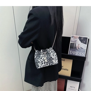 Detailed view of leopard print bucket bag with pearl drawstring and silver chain strap
