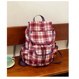 Minimalist red and white checkered nylon backpack with purple straps on a wooden bench