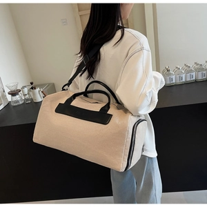 Detailed side view showing reinforced stitching and adjustable strap on beige canvas bag