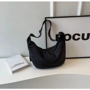 Detail of black nylon dumpling bag with woven zipper pull and adjustable shoulder strap
