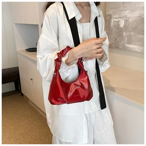 Close-up of a red pleated PU leather underarm bag with glossy finish and half-moon shape