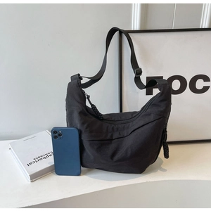 Detailed view of black nylon crescent bag with adjustable strap and front zipper pocket