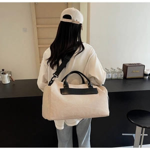 Minimalist canvas travel tote bag with black leather accents shown on a model