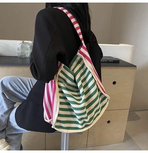 Detail view of the pink and green striped canvas tote bag worn on shoulder as a crossbody