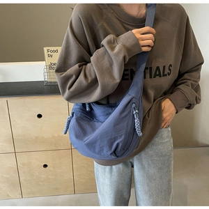 Blue nylon dumpling crossbody bag worn by model showing casual style and large capacity