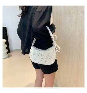 Détail du sac hobo tissé avec broderie florale verte et nœud décoratif élégant
