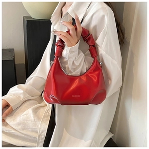 Detail of red PU leather handbag with pleated handle and elegant crescent design