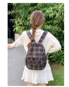 Close-up of a premium plaid tweed backpack with leather strap details on a female model