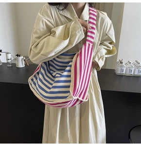 Detail of a large canvas crossbody bag with blue, white and pink stripe patchwork design